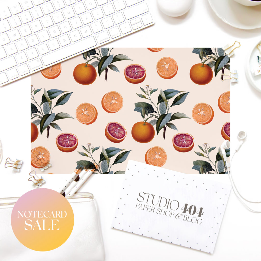 Orange botanical notecard on desk with keyboard, mouse, and Studio 404 Paper business card
