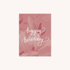 A birthday card with a pink magnolia background with Happy Birthday handlettered in white