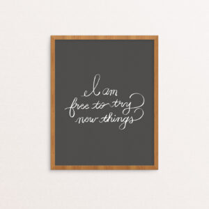 Art print with "I am free to try new things" hand lettered in white on a gray background
