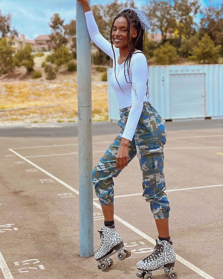 Woman leaning against post outside showcasing her leopard print roller skates